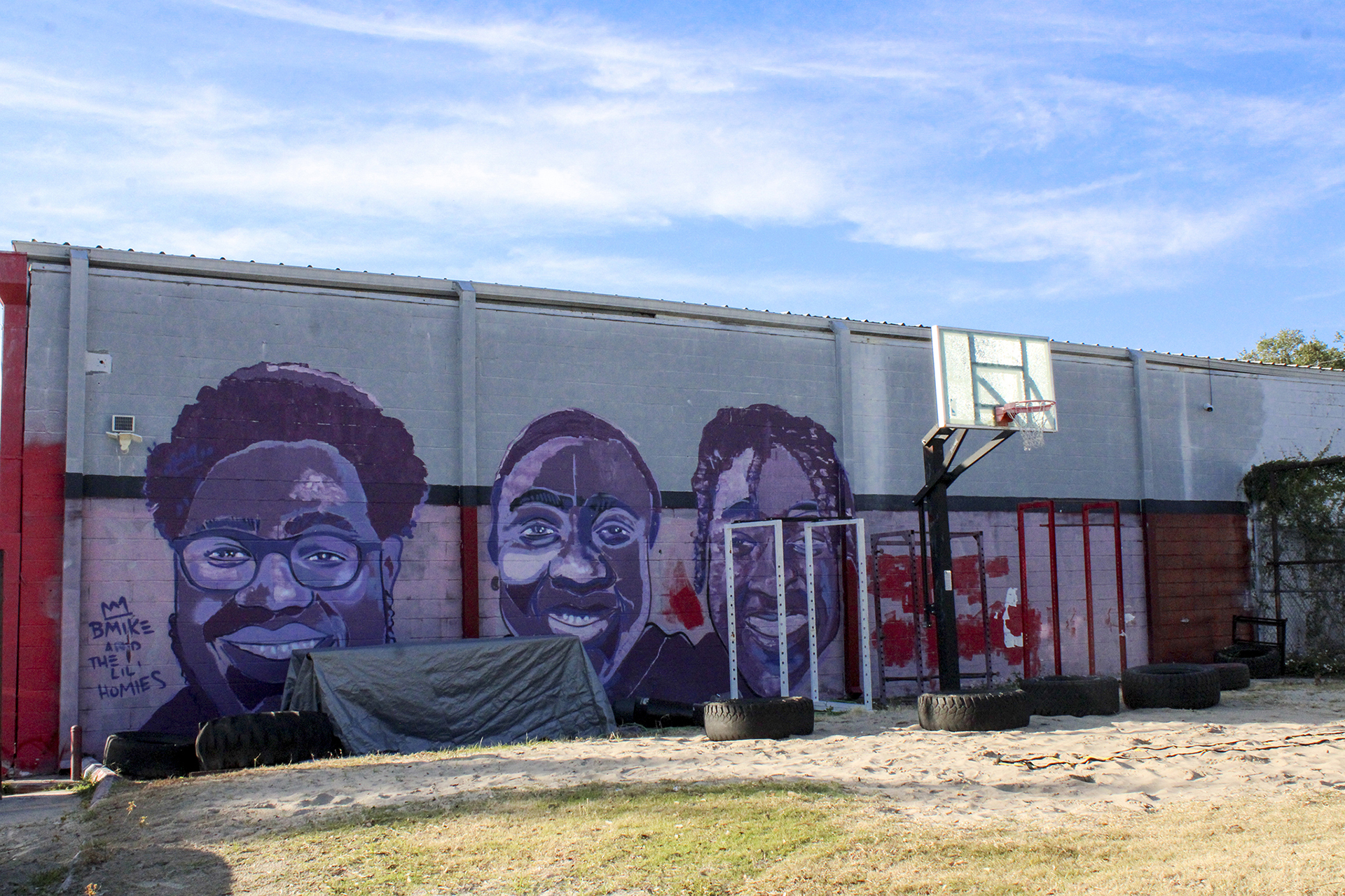 A mural of purple portraits is on the side of the red MT Athletics Building in Uptown New Orleans.