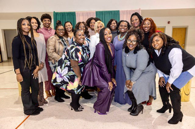 A group of Black women are gathered together and smiling.
